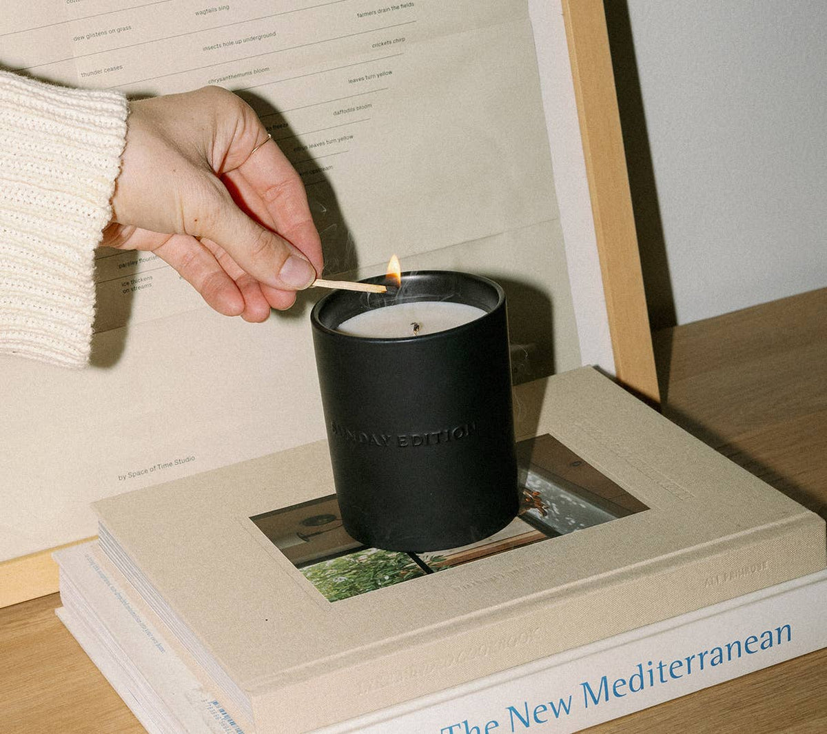 A Sunday Edition candle being lit in its black ceramic vessel