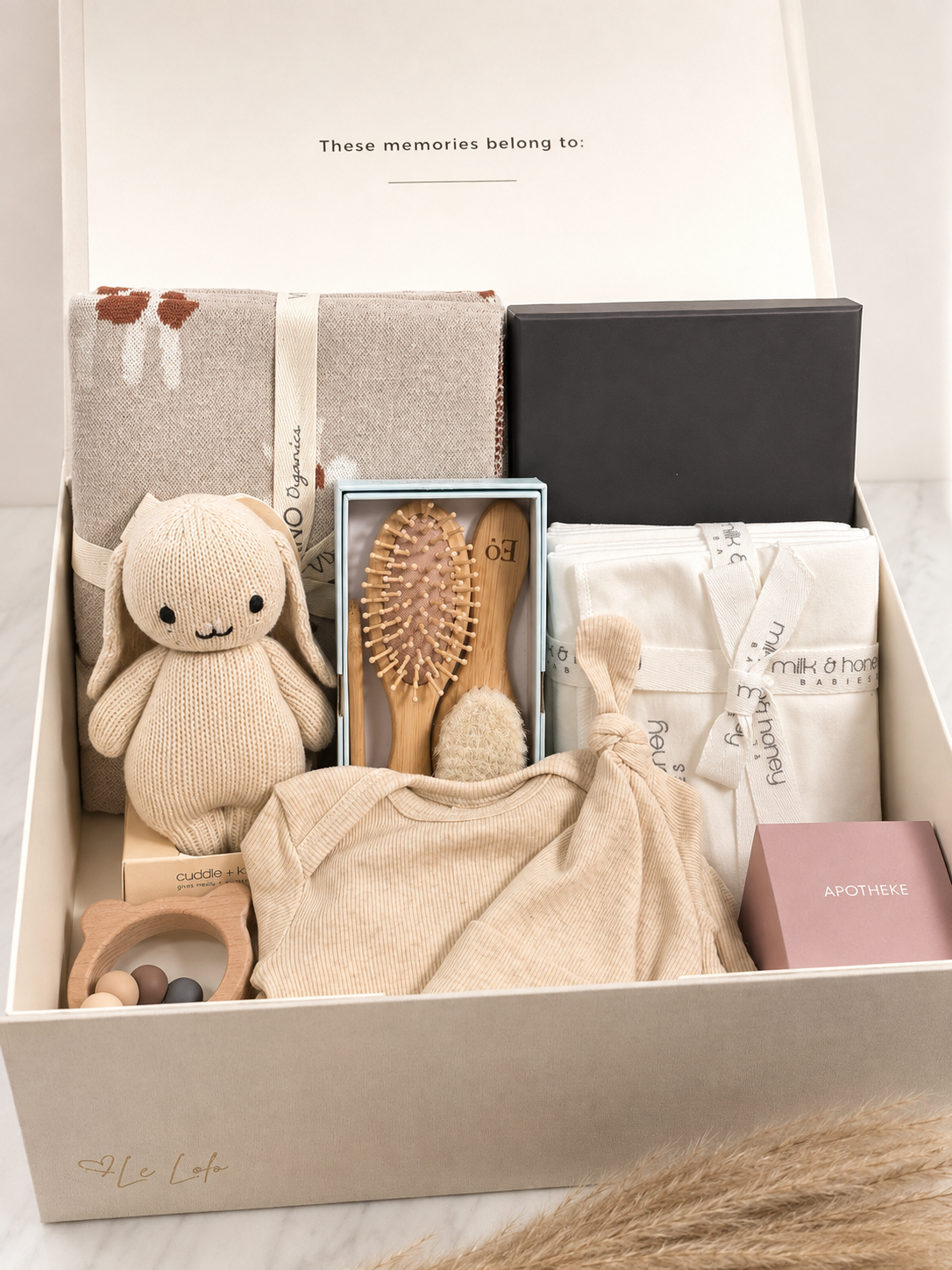 The Keepsake open linen box with knotted gown, hand knit bunny, jacquard blanket, organic burp cloths, bamboo brush set, ring teether, postpartum journal and candle