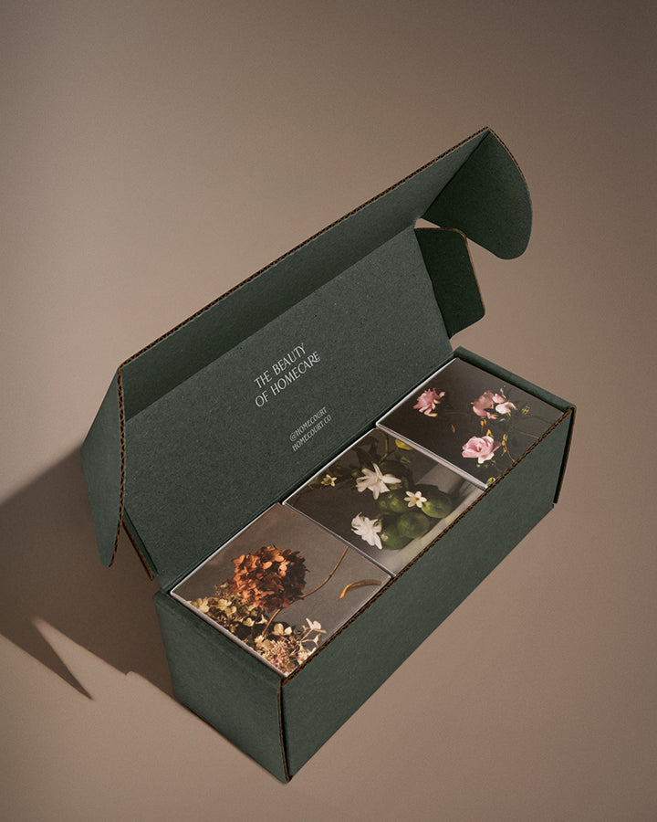 The three signature votives in an open box, floral lids