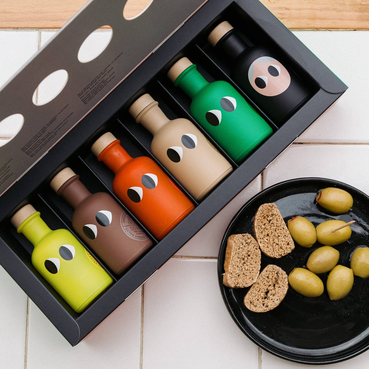 The Mini Olive Oils box open beside bread and olives